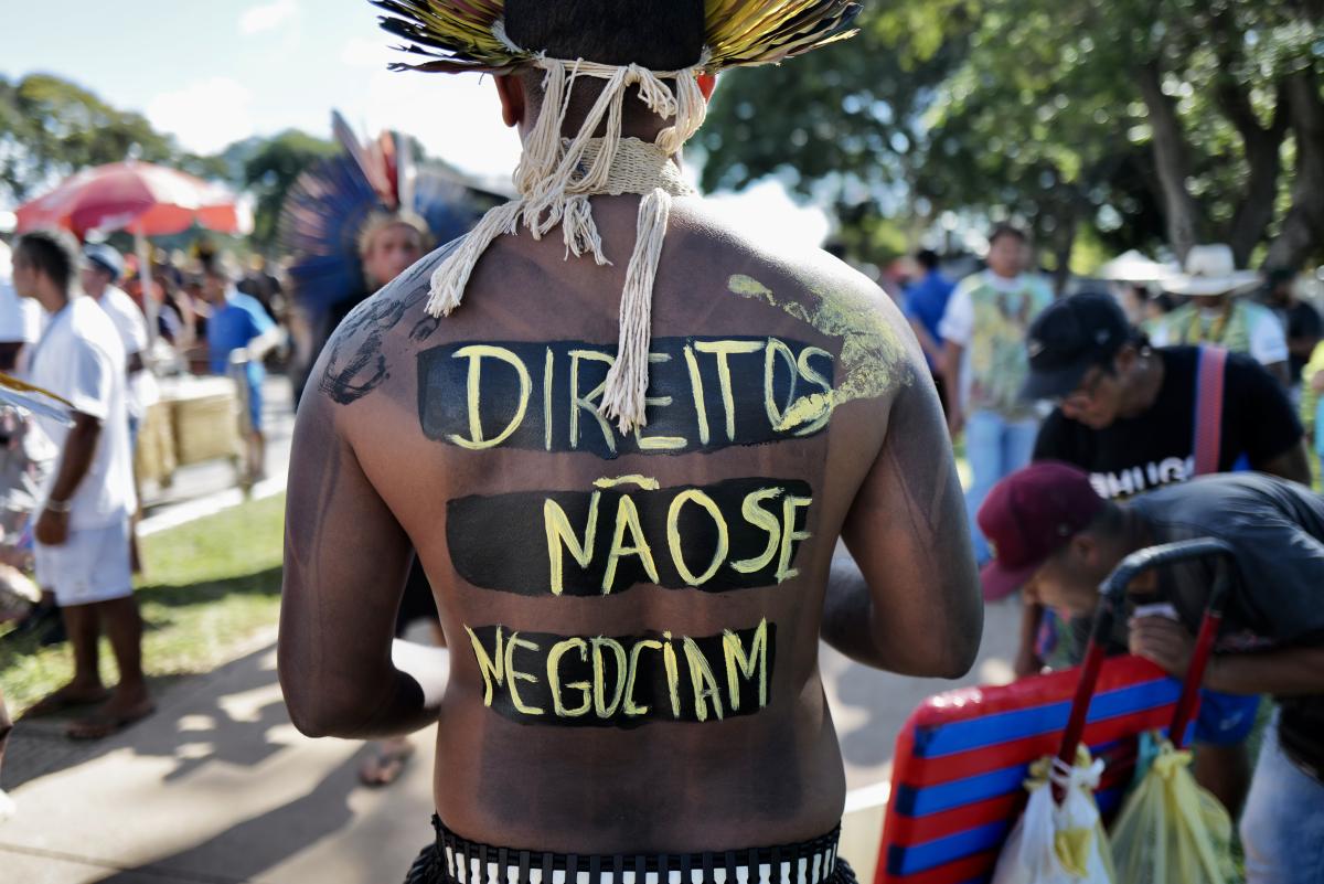 Homem indígena com a frase "Direitos não se negociam" escrito nas costas