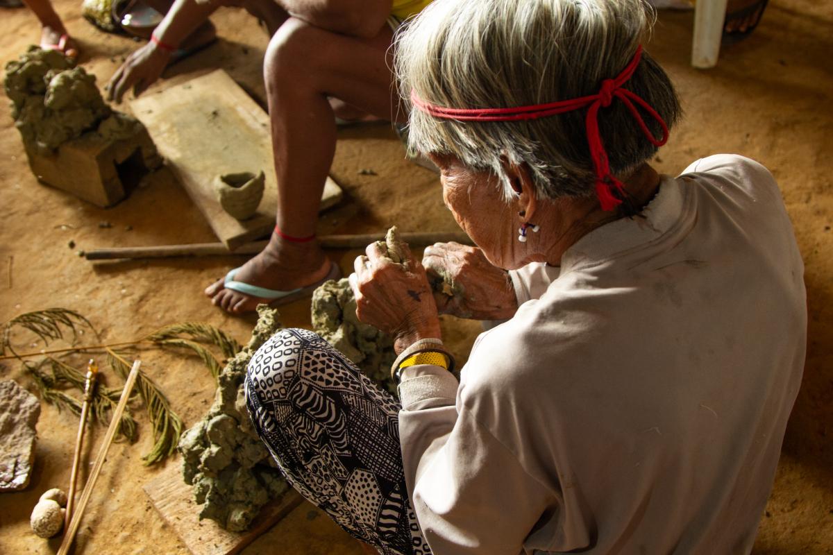 Foto mostra mulher indígena Assurini fazendo peças de cerâmica