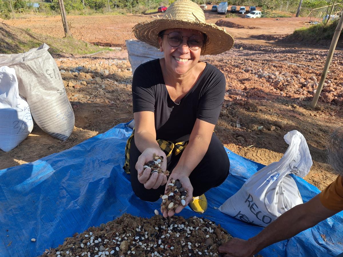 Mulher segura variedade de sementes nas mãos e sorri para foto